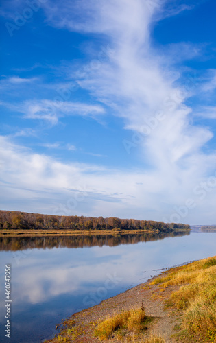 Beautiful, wide river autumn among the woods. Calm and quiet place with autumn colors. In the middle of the river island. View from the top to the distance