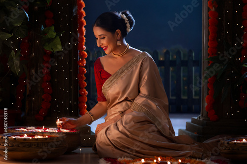 Woman decorating entrance by placing floating diyas on the occasion of Diwali photo