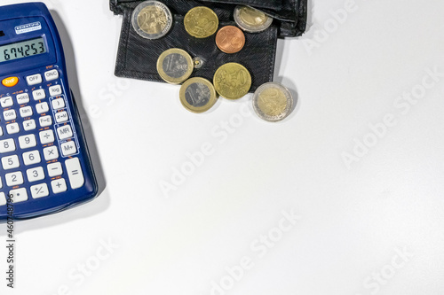 European money with black wallet on white desk as white background with different euro coins and euro bank notes with calculator for financial management and income business plans for tax calculation photo