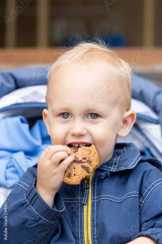 A baby is sitting in a stroller with a cookie in his hand