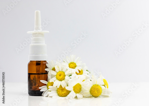 Nasal spray and natural chamomile on a white background. Treating seasonal allergies. Banner, side view, place for text.