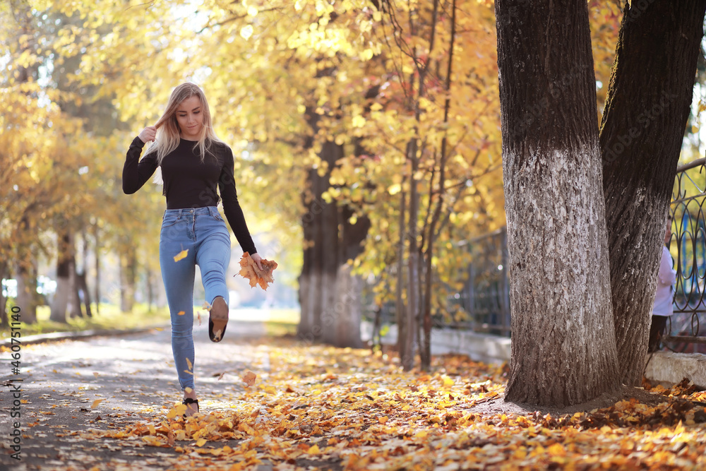 Young beautiful girl on a walk in the autumn park. Leaf fall in the city park. October. Young beautiful girl on a walk in the autumn park. Leaf fall in the city park. October.