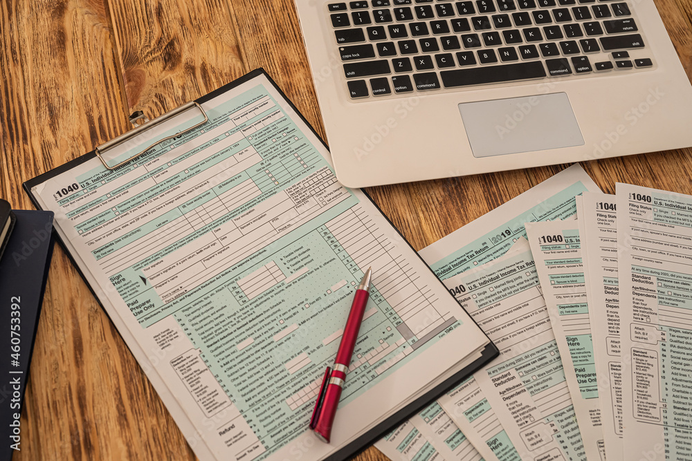 Obraz premium on a wooden table lie a laptop, American tax forms with a tablet and a pen