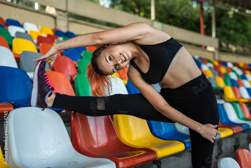 female trainer doing yoga or pilates exercise against green stadium background