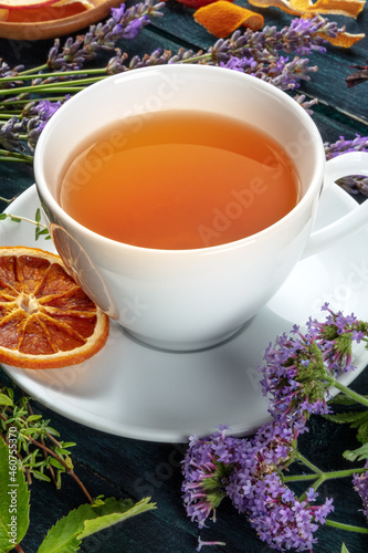 Herbal tea. Herbs, flowers and fruit around a cup of tea on a dark rustic wooden background
