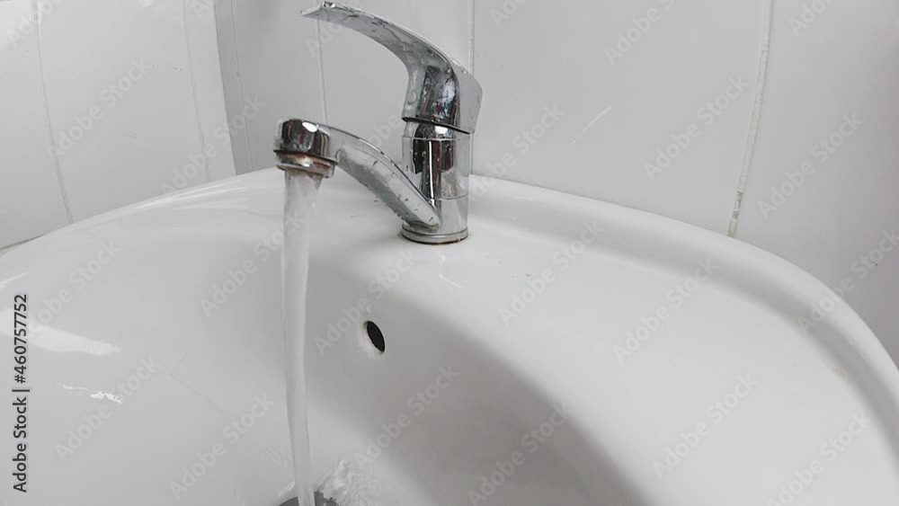 Flowing running faucet water. Faucet with running water in the simple white bathroom Flowing running faucet water. Faucet with running water in the simple white bathroom