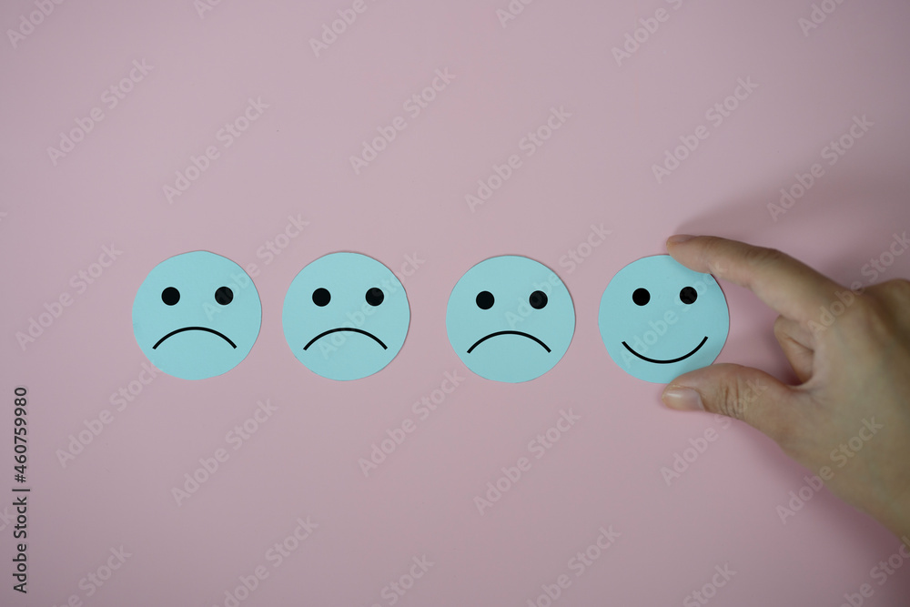Hand holding happy face smile face icon paper cut on pink background, Customer service evaluation and satisfaction survey concept. Hand holding happy face smile face icon paper cut on pink background, Customer service evaluation and satisfaction survey concept.