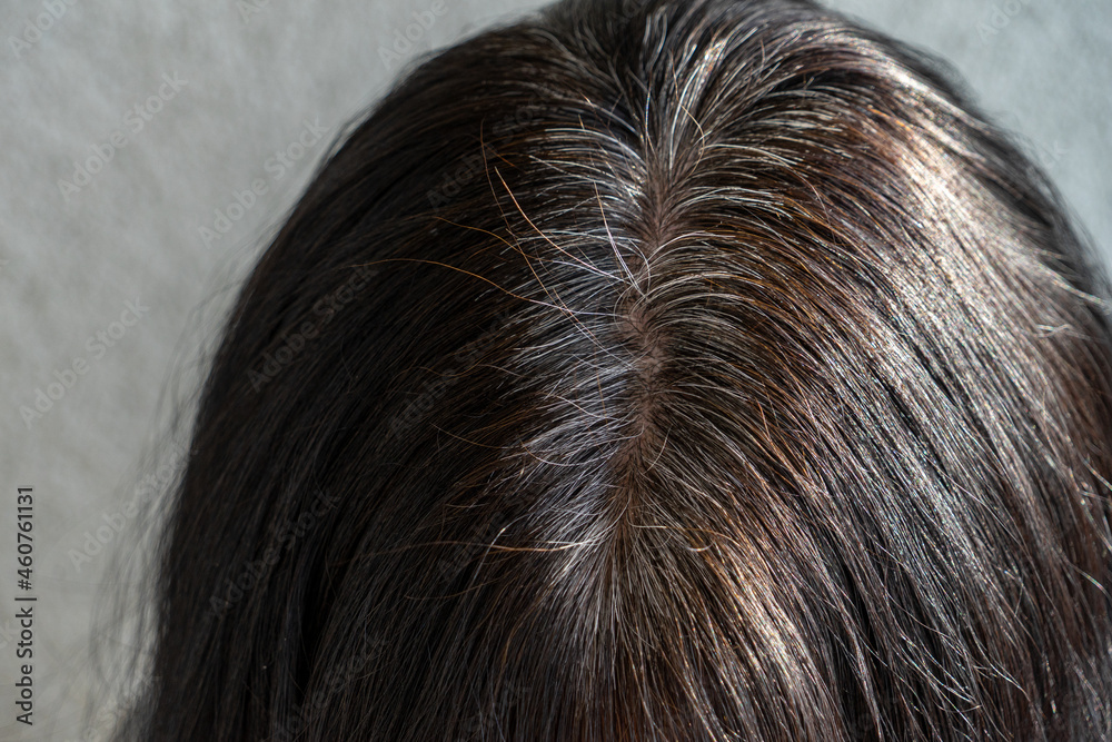 Close up of middle age caucasian woman with dark brown hair and regrown gray hair roots. View from above Close up of middle age caucasian woman with dark brown hair and regrown gray hair roots. View from above