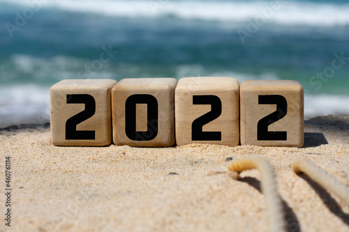 wooden cube written 2022 on the beach sand.