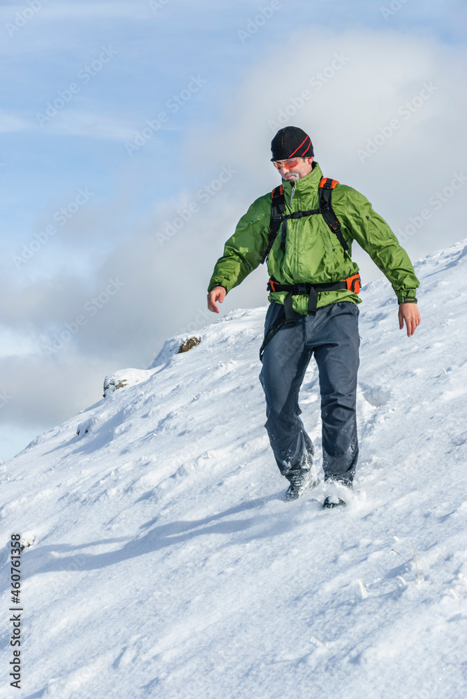 Wanderer beim Abstieg über einen verschneiten Hang