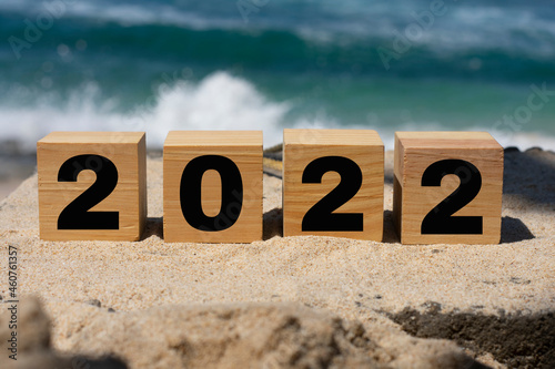 wooden cube written 2022 on the beach sand.
