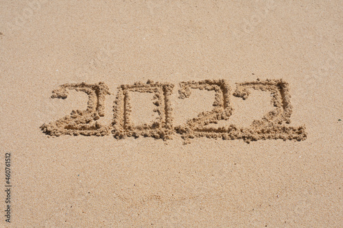 wooden cube written 2022 on the beach sand.