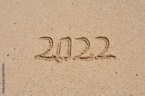 wooden cube written 2022 on the beach sand.