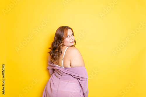 Sexy plus size young woman in lingerie with sensual pose from behind in silk robe