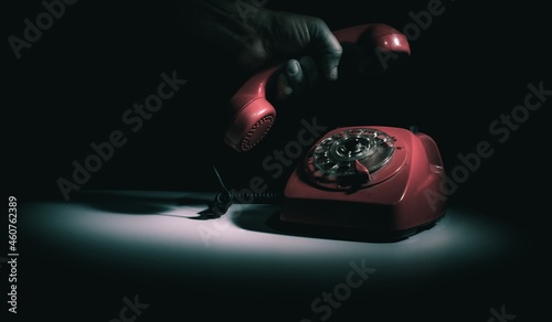 hallo, anybody there, old dial telephone in red with a male hand, holding the handset 