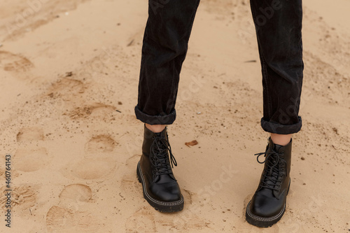 girl's feet in black boots on the sand