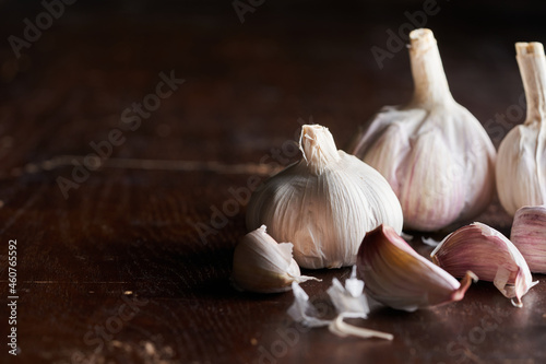 Rustic composition of bulbs and cloves of garlic on a dark wooden underground