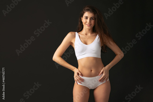 Portrait of young beautiful slim woman in lingerie posing isolated over dark studio background. Natural beauty concept. © master1305