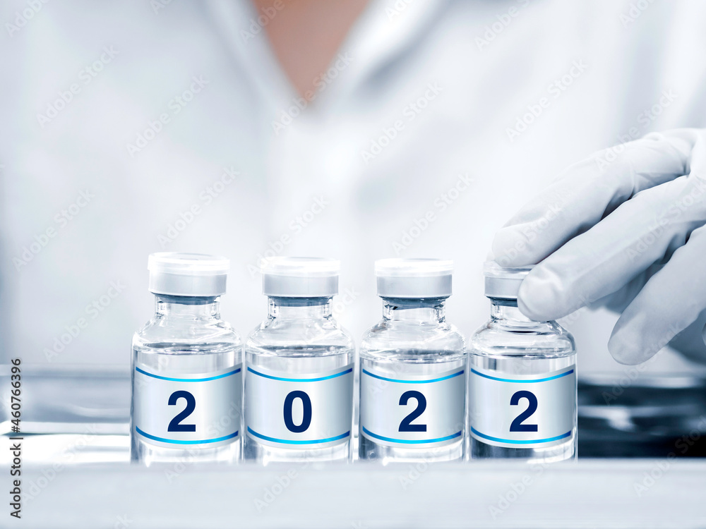 The 2022 year numbers on label on vaccine vials in hand with glove. Four glass bottles with vaccine drug against covid-19 virus remedy for epidemic of coronavirus immunization. Vaccination concept. The 2022 year numbers on label on vaccine vials in hand with glove. Four glass bottles with vaccine drug against covid-19 virus remedy for epidemic of coronavirus immunization. Vaccination concept.