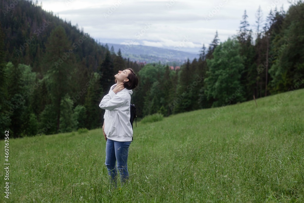 Woman traveler standing on a glade high in the mountains in front of forest, space for text, atmospheric epic moment Woman traveler standing on a glade high in the mountains in front of forest, space for text, atmospheric epic moment