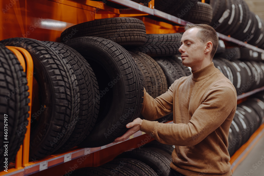 Man chooses winter car tires in the auto shop - obrazy, fototapety, plakaty 