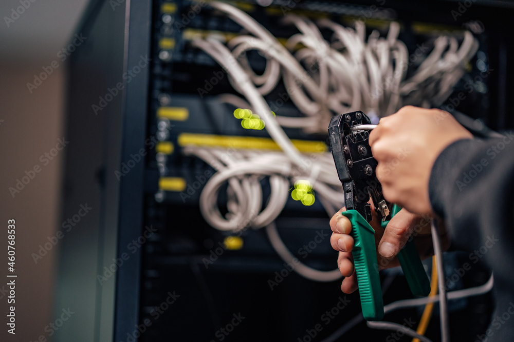 Fototapeta premium Technician installing a new connector on ethernet cable using crimping tool.