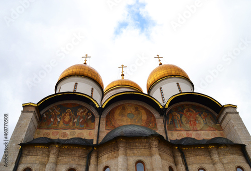 Golden bells in the Assumption Cathedral in the Kremlin. Ornate arches surrounded by paintings.was built between 1475 and 1479