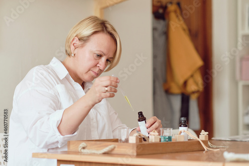 Close-up of a pipette with oil and a glass bottle. woman pouring perfume in bottle. Perfume creating workshop photo