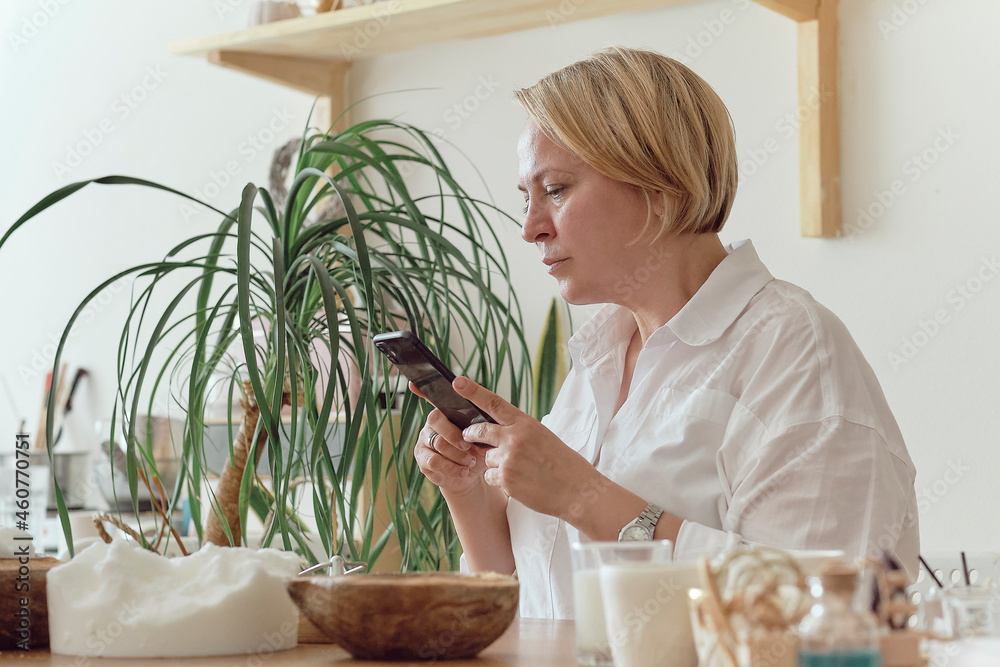 woman entrepreneur makes stylish photos on a smartphone to advertise herself on social networks. promotion in the internet, smm