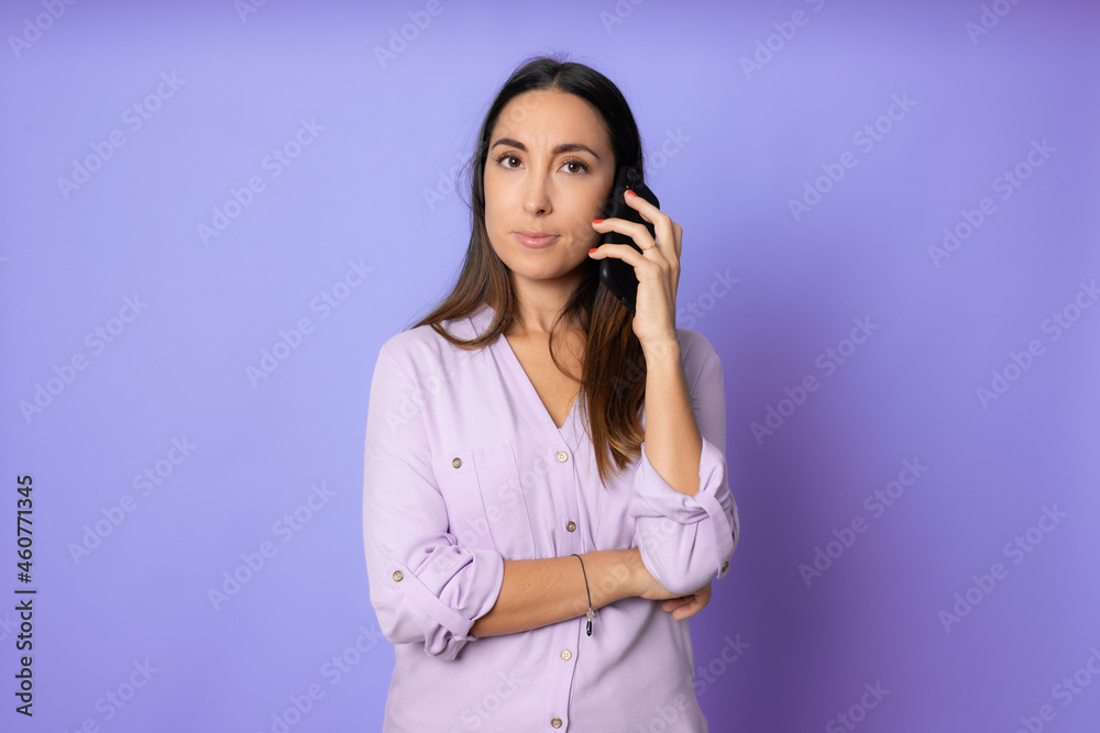 Serious young woman talking on phone isolated on purple. Copy space and fashion. Mock up. Serious young woman talking on phone isolated on purple. Copy space and fashion. Mock up.
