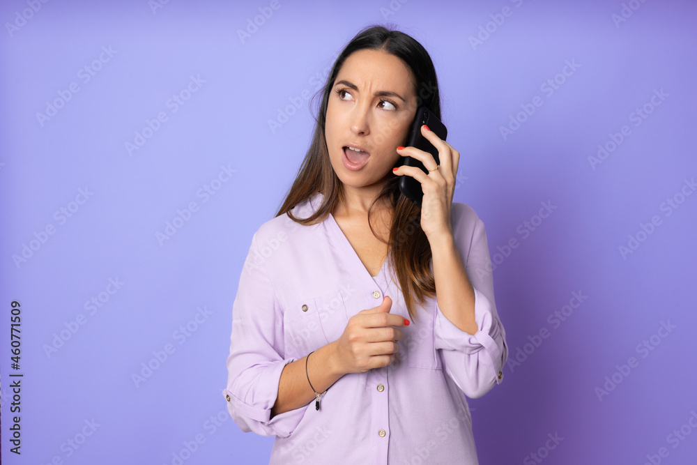 Angry young woman talking on phone isolated on purple. Copy space and fashion. Mock up. Angry young woman talking on phone isolated on purple. Copy space and fashion. Mock up.