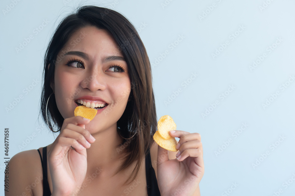 Woman eating potato chips or crispy fried potato, health and medical concept of unhealthy food, high sodium and saturated fat fried food, unhealthy lifestyle, bad breath, oral care Woman eating potato chips or crispy fried potato, health and medical concept of unhealthy food, high sodium and saturated fat fried food, unhealthy lifestyle, bad breath, oral care