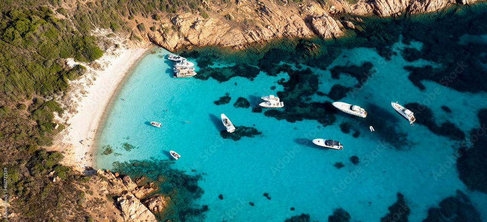 View from above, stunning aerial view of Mortorio island with a beautiful white sand beach and some boats and yachts floating on a turquoise, crystal clear water. Sardinia, Italy.
