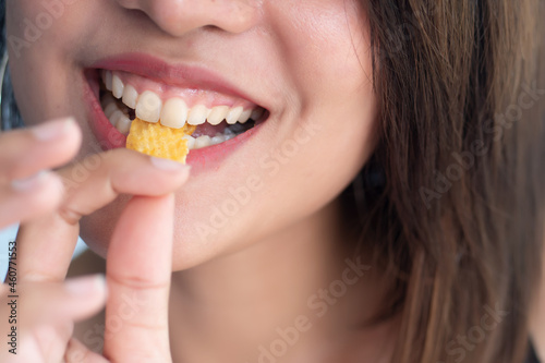 Woman mouth eating potato chips or crispy fried potato  health and medical concept of unhealthy food  high sodium and saturated fat fried food  unhealthy lifestyle  bad breath  oral care