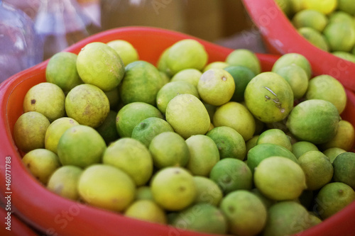 A bunch of lemons in a basket at an outdoor vendor.