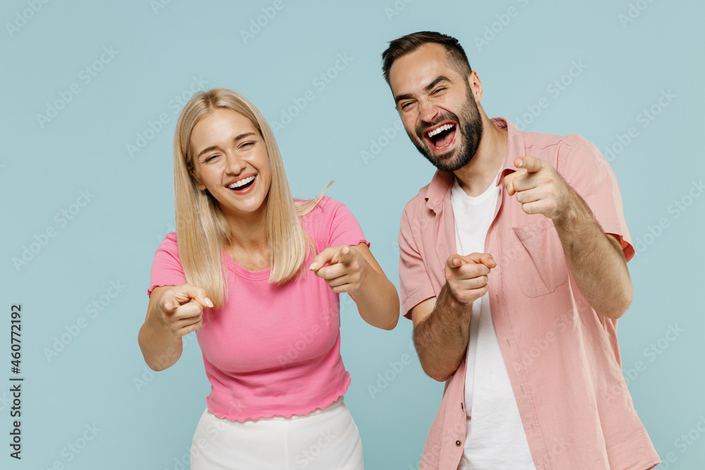 Young fun couple two friends family man woman in casual clothes point fingers camera on you joking laugh camera together isolated on pastel plain light blue background studio People lifestyle concept. - obrazy, fototapety, plakaty 