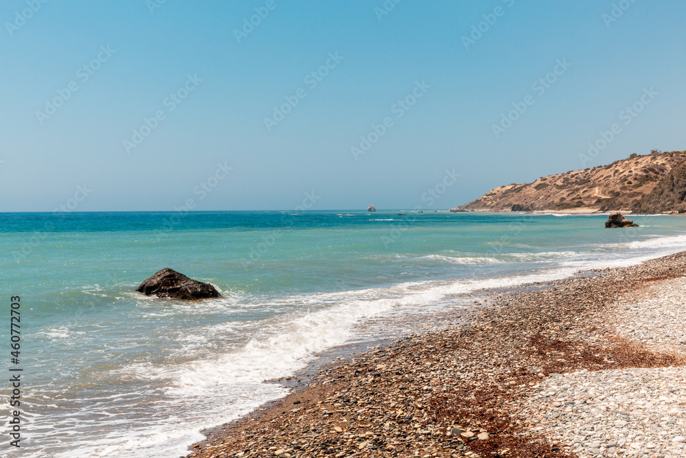 View of Aphrodite Beach. Afternoon at the sea. Bright sun, foam from the wave, pebble beach. Large stones on the beach, beautiful sea view. Legends of Greece. Aphrodite.