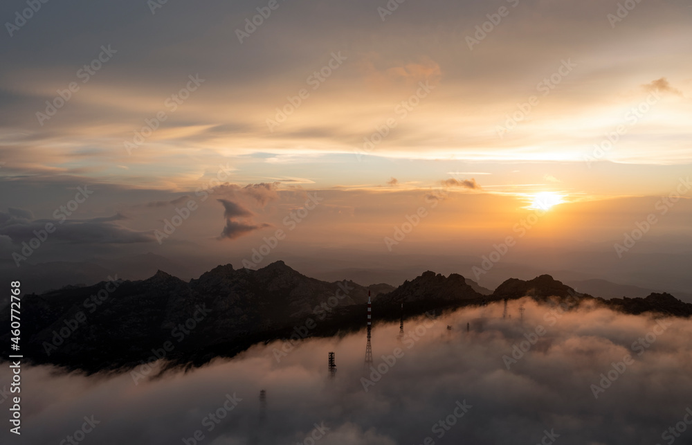 View from above, aerial view of a mountain range with an antenna farm surrounded by clouds during a stunning sunrise. Mount Limbara (Monte Limbara) Sardinia, Italy.