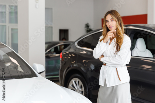 Pensive thoughtful woman customer female buyer client in white shirt prop up chin choose auto want to buy new automobile in car showroom vehicle salon dealership store motor show indoor Sales concept © ViDi Studio