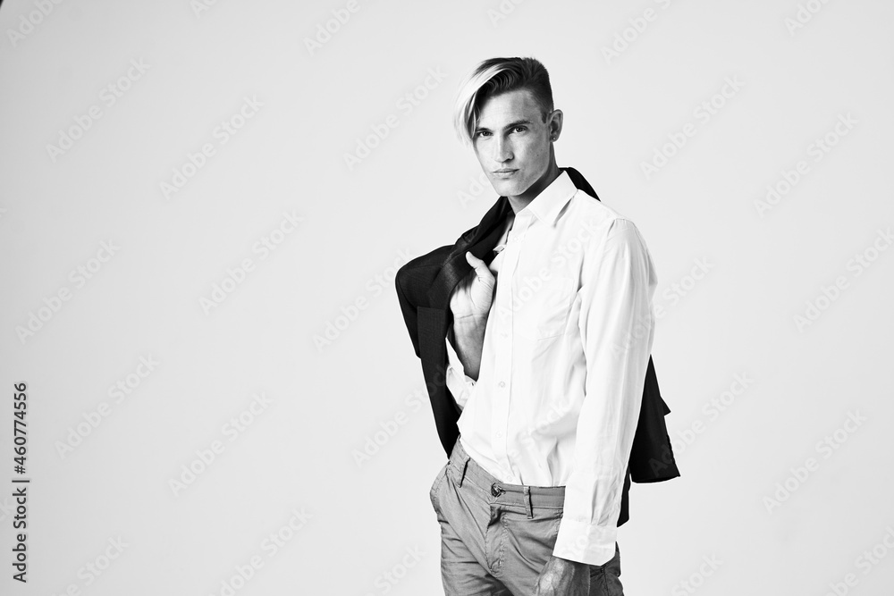 man in a white shirt with a jacket on his shoulder fashionable hairstyle posing light background