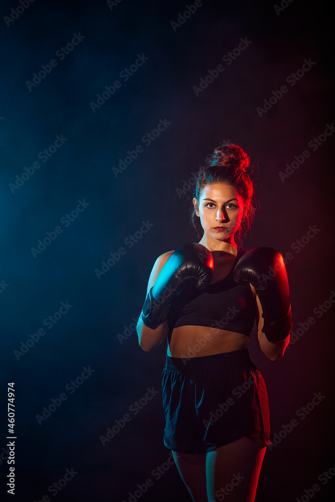 woman practicing boxing or kickboxing with colored lights and smoke