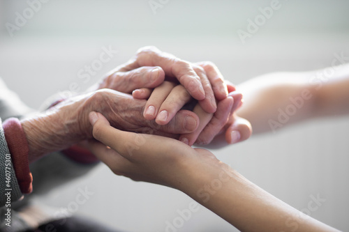 The hands of the child in the hands of the grandmother, the old brownish skin in the elderly woman, motherly love and care. photo