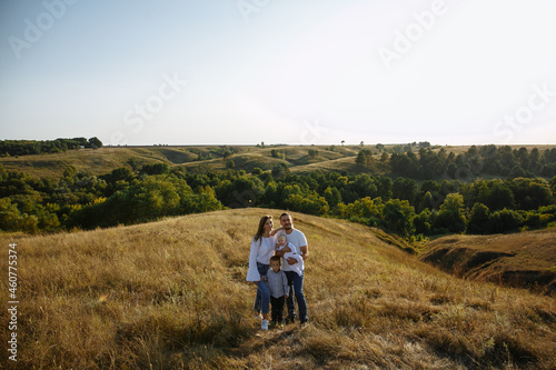 family with small children on a background of hills among a field of grass © Andrii