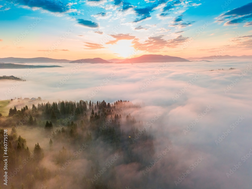 Obraz premium Fog spreads over the mountains at dawn. The sun rises on the horizon. Ukrainian Carpathians in the morning. Aerial drone view.
