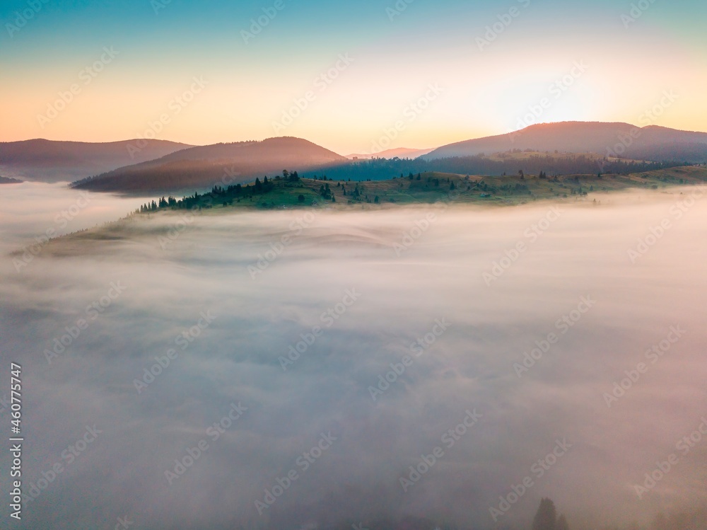 Fog spreads over the mountains at dawn. The sun rises on the horizon. Ukrainian Carpathians in the morning. Aerial drone view. Fog spreads over the mountains at dawn. The sun rises on the horizon. Ukrainian Carpathians in the morning. Aerial drone view.