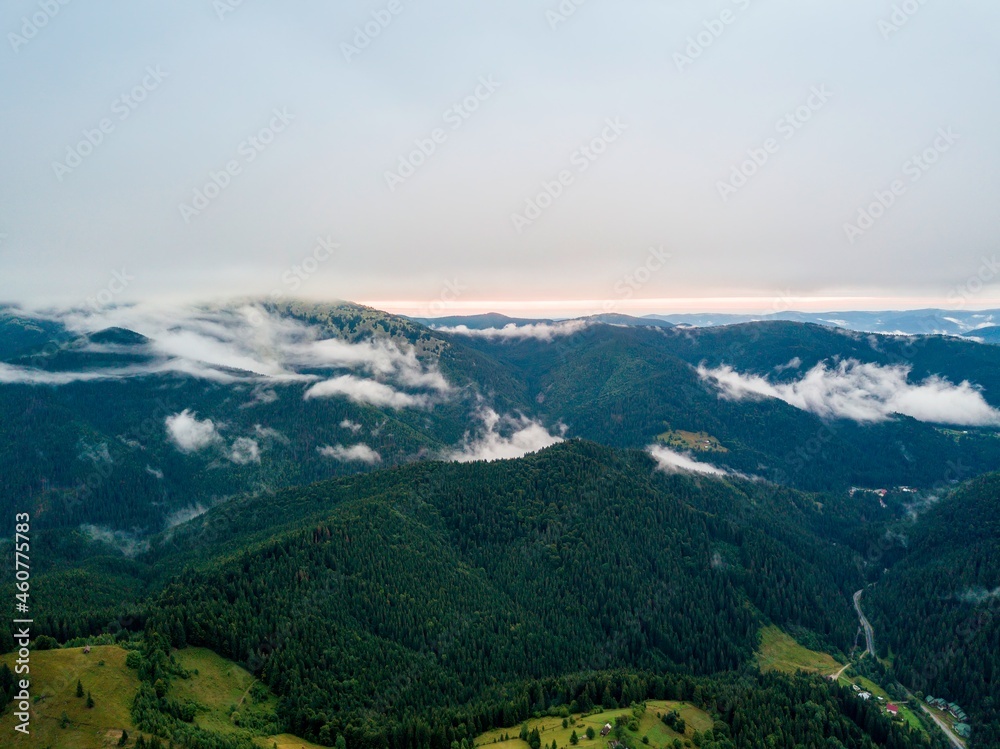 High flight among the clouds at dawn. Ukrainian Carpathians in the morning in the haze. Aerial drone view.