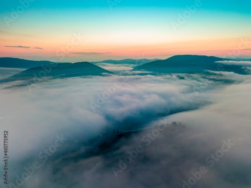 Fog in the mountain valley at dawn. Ukrainian Carpathians in the morning in the haze. Aerial drone view.