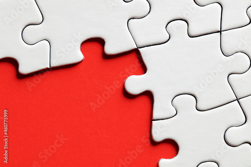 Red background surrounded by white jigsaw puzzle pieces with copy space.