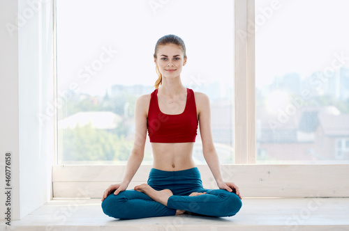 woman sitting on the windowsill near the window yoga exercise slim figure