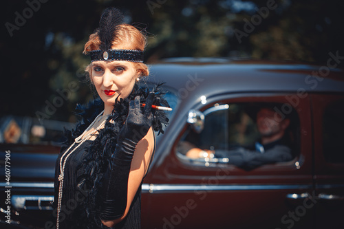 Young woman standing near retro car where man sits